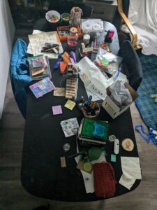 A black table strewn with craft supplies, books, treats, and paper.s 