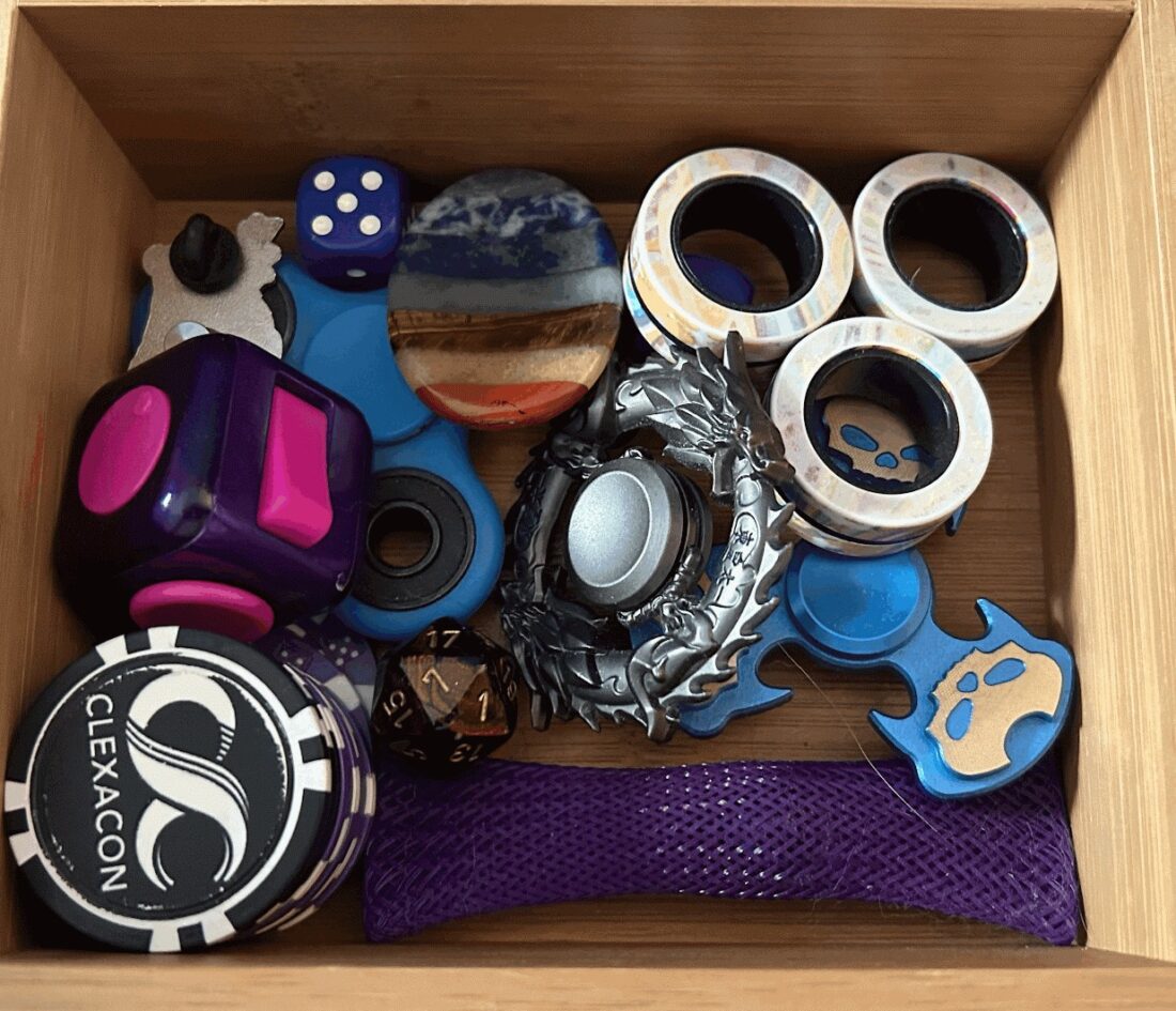 A wooden drawer full of various fidget tools.