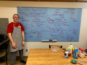 Ashton in an apron in front of a filled whiteboard