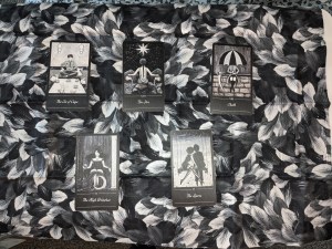 Five black and white Tarot cards against a black and white cloth