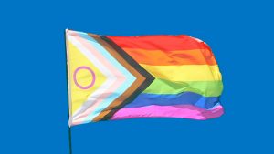 The new progress pride flag flying in a blue sky
