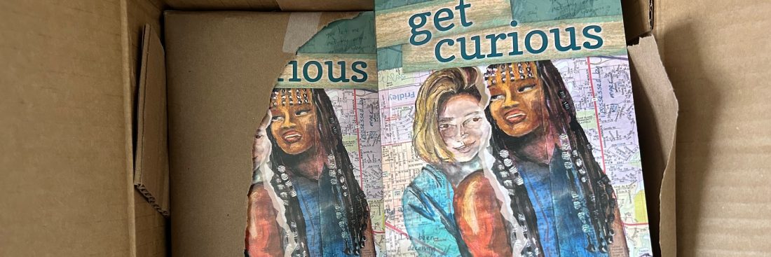 Teal and green books, Get Curious, partially covered in a box