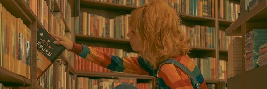 young woman picking up a book in a library